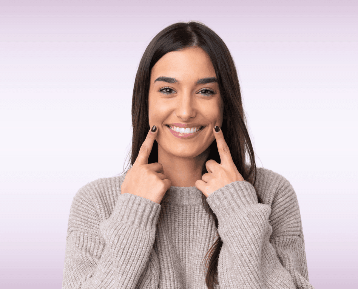 Woman smiling and pointing to her beautiful teeth after dental bonding treatment