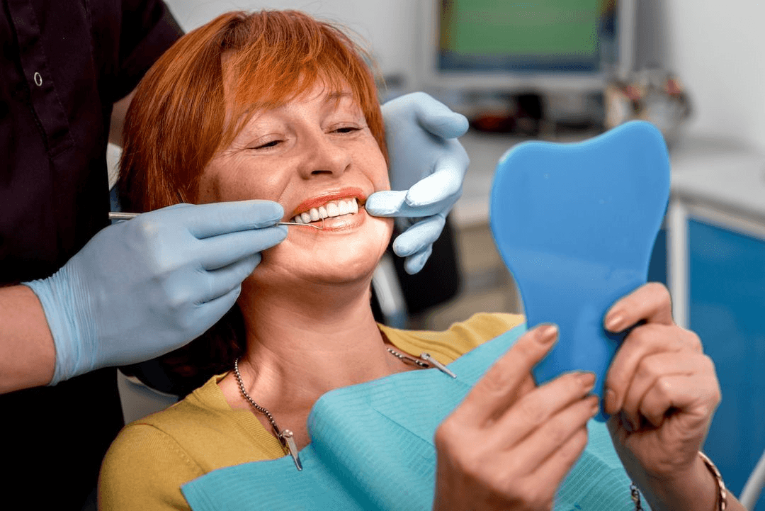 Patient smiling while reviewing her new smile after full mouth reconstruction at Esthetique Dentistry Ashburn