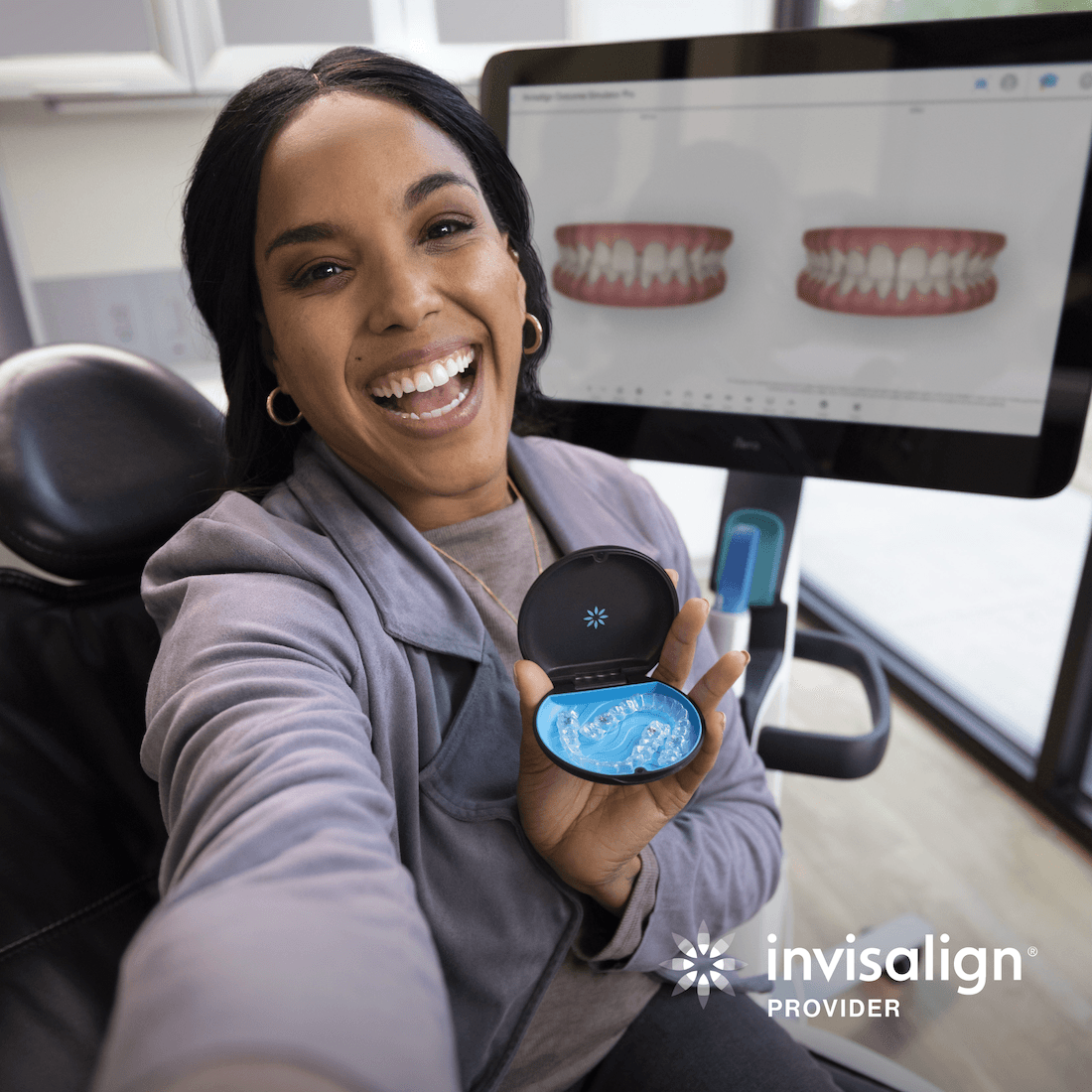 Smiling Invisalign patient holding clear aligners at Esthetique Dentistry Ashburn