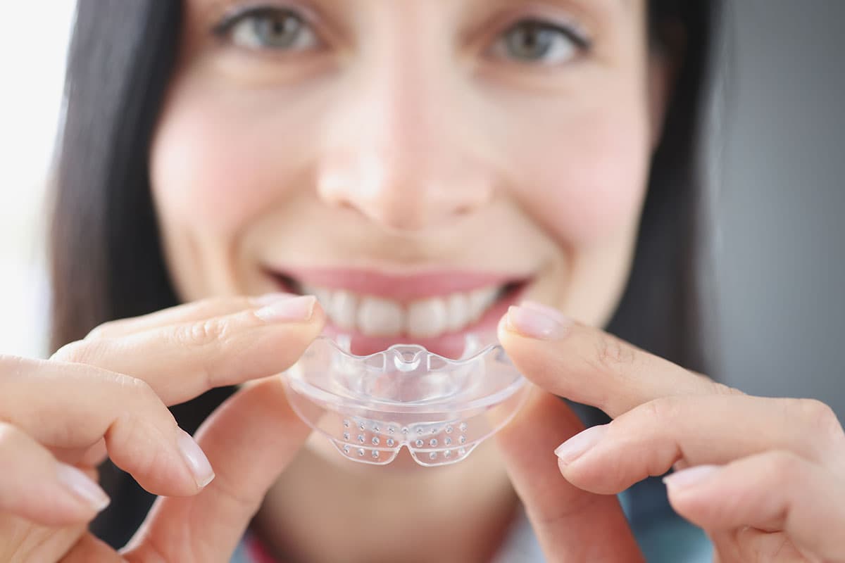 Woman holding a custom clear mouthguard at Esthetique Dentistry Ashburn