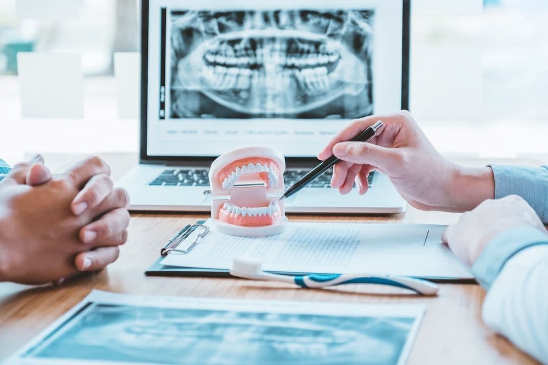Dentist explaining oral surgery procedure with dental model and X-ray in Ashburn VA