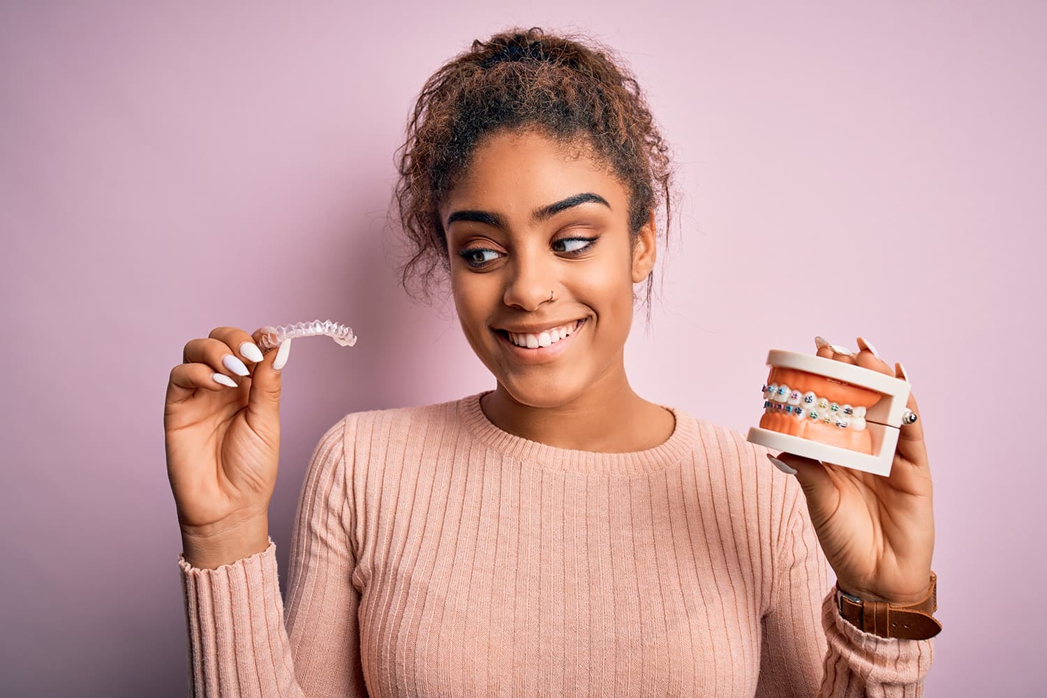 Woman comparing Invisalign clear aligners with traditional braces in Ashburn VA